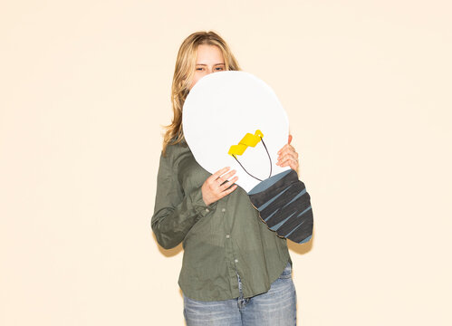 Woman holding a paper lightbulb cutout symbolizing a creative idea
