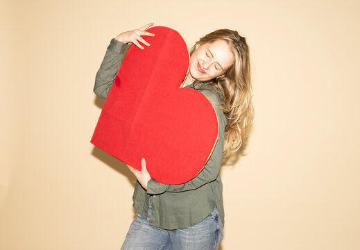 Woman hugging a large red paper heart expressing love and empathy