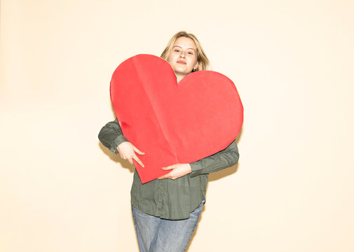 Woman holding a large red paper heart showing love and core values