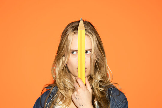 Student holding giant pencil over face exploring creativity