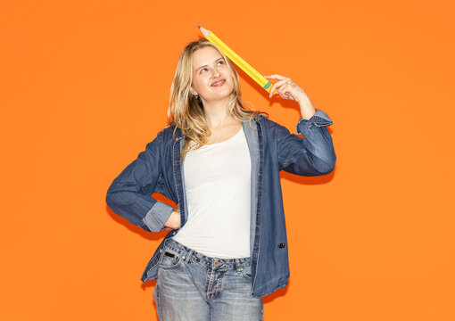 Creative woman holding oversized pencil while brainstorming ideas