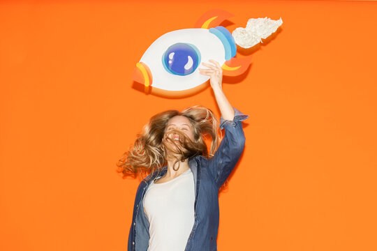 Female entrepreneur jumping with handmade paper rocket for success