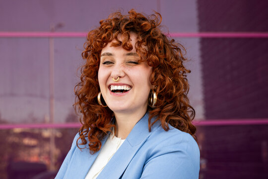 Smiling entrepreneur in blue blazer winking outdoors in Granada