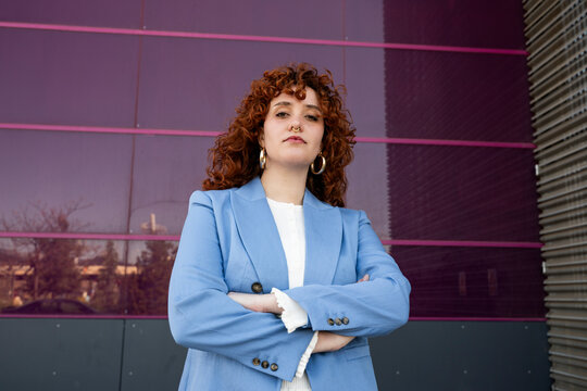Confident entrepreneur in blue blazer with arms crossed outdoors