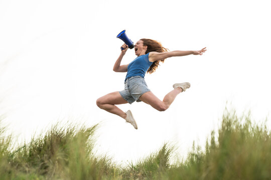 Activist jumping outdoors and shouting into a megaphone