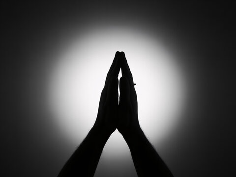 Hands together in prayer silhouette, black and white, spiritual gesture