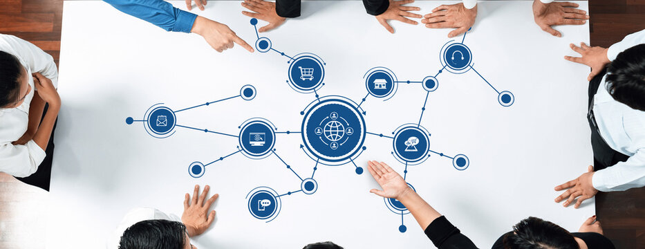 A diverse business team collaborates around a modern table, focusing on a digital strategy. The visual includes connectivity icons and e-commerce elements, showcasing teamwork and innovation. Amity