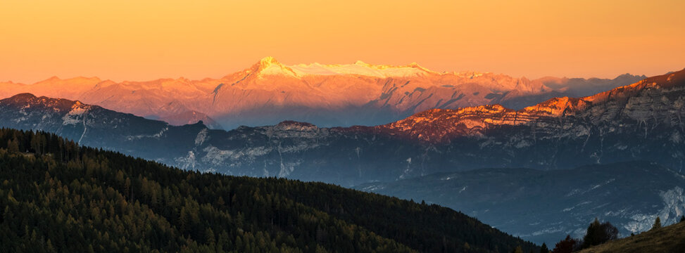 Dolomite mountains landscape at golden sunset, featuring layered peaks and dark forests, perfect for nature tourism, adventure and copy space. Brenta Dolomites from Paganella plateau, Trentino, Italy.