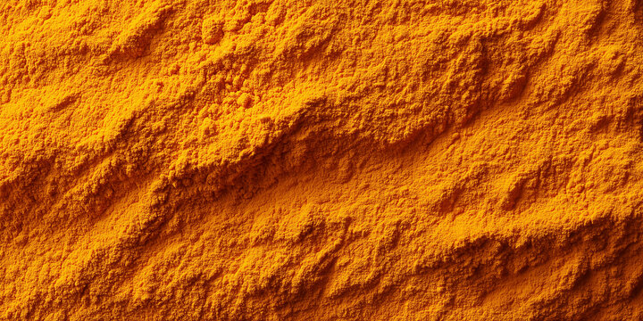 a vibrant warm orange background texture of finely ground turmeric powder in a uniform layer
