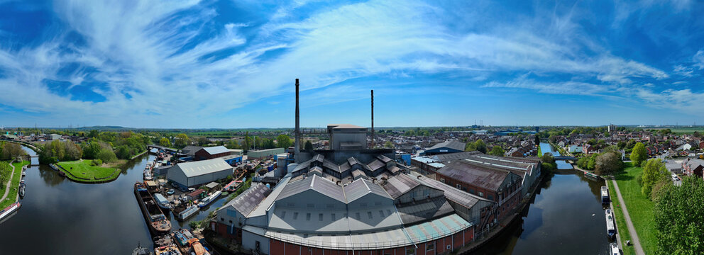 Aerial view of the industrial complex and canal with moored barges under a bright blue sky in Knottingley, England, United Kingdom.