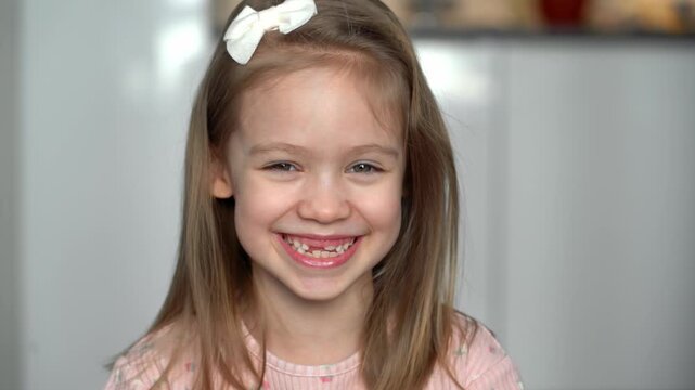 Portrait of happy toothless girl looks at camera and laughs. Close up of face of child. Baby milk teeth change