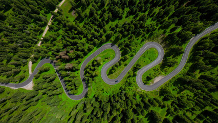 Naklejka premium Winding mountain road, aerial view of a serpentine asphalt highway through a dense green forest, scenic travel route for adventure and exploration, nature landscape photography