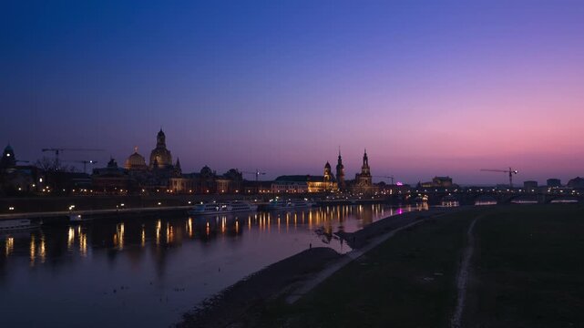 Day-to-night hyperlapse of Dresden skyline along the Elbe River, Germany. The scene captures a smooth transition from sunset to dusk and into night, with the historic Old Town skyline including Frauen