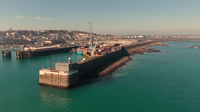 St Peter Port Harbour Guernsey.Drone flight towards ferry berth and docks on bright sunny afternoon with calm clear blue water with backdrop of town and QEII marina