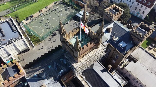 Elizabeth College St Peter Port Guernsey circling,low overhead footage of its beautiful tower with flag flying in late afternoon sun