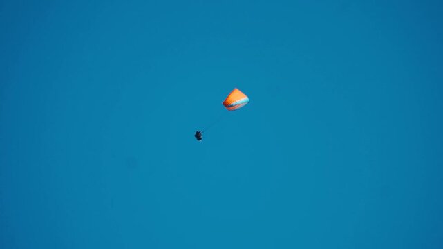Paragliding in the blue sky during summer day at Manali, Himachal Pradesh, India. Tourist enjoying thrill and freedom of paragliding. Concept of adventure sports and outdoor enthusiasts.