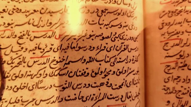Landscape tilt-down shot of an ancient Arabic manuscript revealing rows of handwritten text and historical annotations on textured old paper