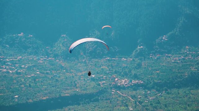 Group of paragliders at Manali in Himachal Pradesh, India. Tourist enjoying adventure activity during summer vacation. Adventure activity during summer vacation.