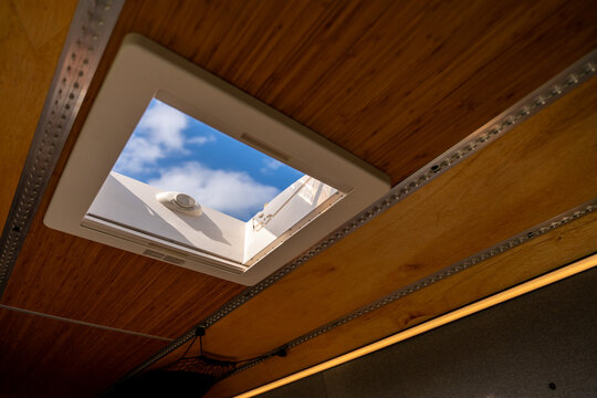 Modern camper van interior detail featuring a skylight window and integrated LED lighting in a high-quality wooden ceiling finish.