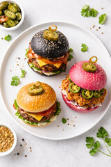 Fototapeta premium Colorful gourmet burgers served on a white plate with toppings