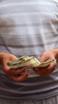 Close up of an Indian man counting five hundred rupee notes outdoors, male hands holding and counting Indian currency cash, finance and investment concept
