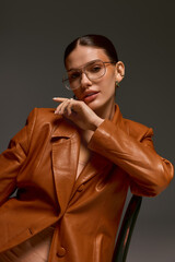 Obraz premium Stylish young woman in leather coat showcases modern fashion in studio setting
