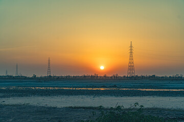 Naklejka premium Haridwar Outskirts in Uttarakhand Sunset over river with power towers