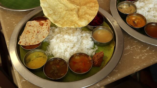 Indian vegetarian platter Thali meals. Having paneer butter masala dal makhani flat bread or naan and rice served in a steel plate and banana leaf Tamil Nadu, Bangalore Karnataka India.	