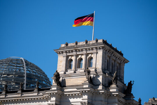 National flag of Germany fluttering on a flagpole at the Reichstag building. Bundesflagge on the Deutscher Bundestag, German Federal Parliament, seat of government on April 21, 2026 in Berlin, Germany