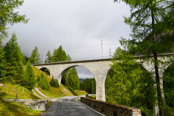 Fototapeta premium Das historische Albulaviadukt III der Rhätischen Bahn über der Passstraße nahe Bergün in der Schweiz