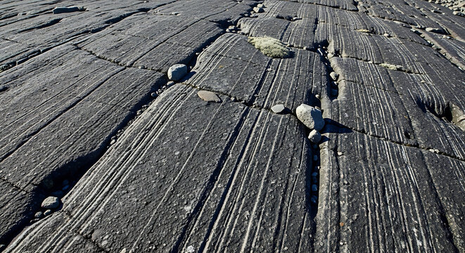 Striated rock surface with natural linear patterns and scattered stones