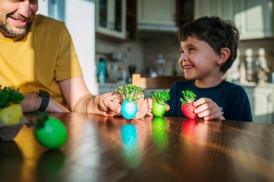 Family holding eco microgreens in colorful Easter eggs at home