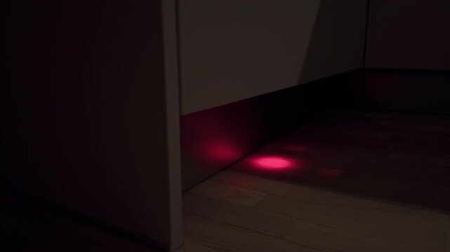 Mysterious laser on corridor floor. Unseen laser spot suggests concealed device in hallway environment