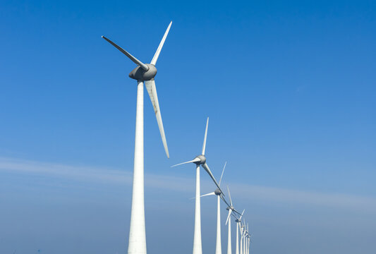 Aerial view of a row of modern wind turbines standing tall against a clear blue sky Netherlands.