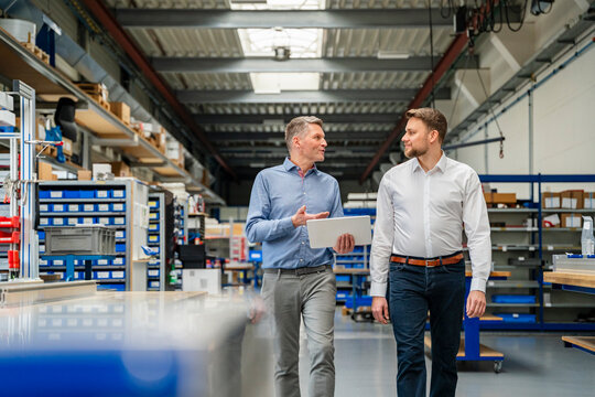 Manager and engineer with tablet talk in production hall