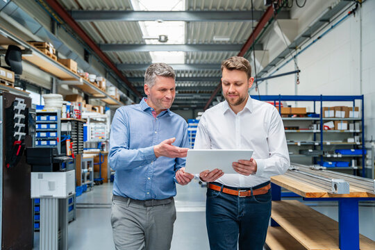 Manager and engineer discuss planning on tablet in production hall