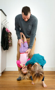 Father holding child upside down while playing indoors