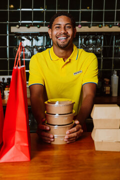 Smiling employee holding takeaway food at restaurant counter
