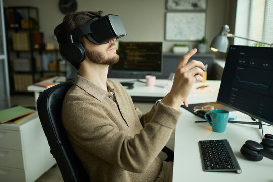 Professional wearing VR goggles working at desk in office