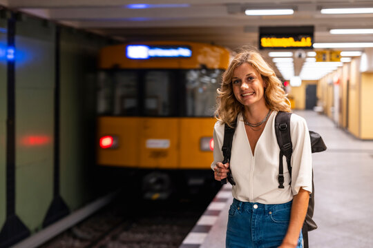 Smiling woman with backpack waiting at underground train in Berlin