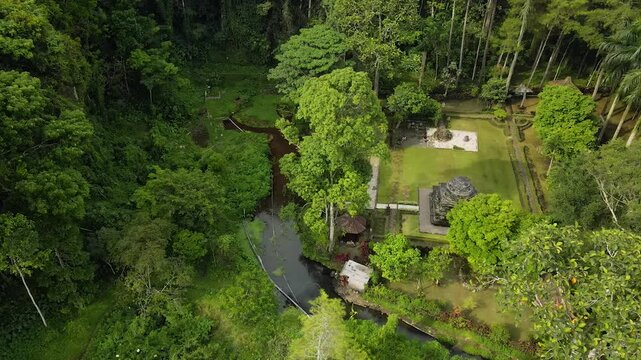 Aerial 4K view of an ancient stone temple in a lush tropical garden in Indonesia.