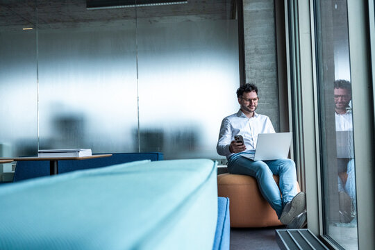Businessman working on laptop and smartphone in modern office