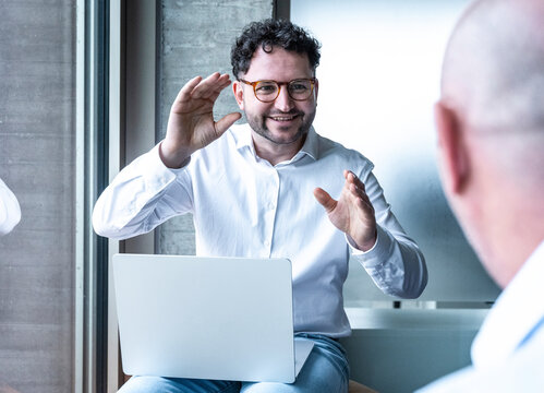Smiling businessman gesturing while discussing work with colleague