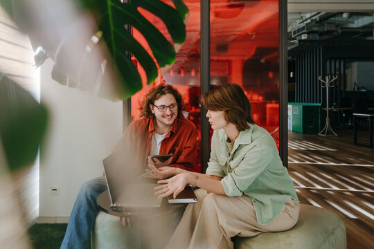 Colleagues discussing strategy with laptop in modern office