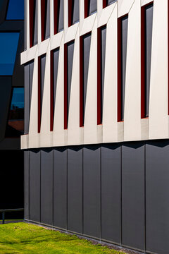Grass foreground meets stripes pattern in contrast on a modern minimalist building facade delivering geometric architecture with clean bold graphic rhythm