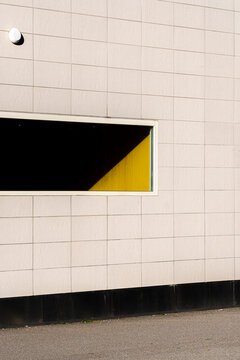 Bold shadow and contrast shape a geometric opening in color on a modern minimalist building wall revealing clean architecture with negative space
