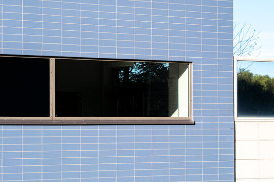 Geometric window set in color contrast tiles defines a modern minimalist building facade with clean architecture detail and bold exterior form