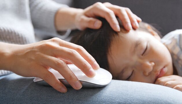 Stroking sleeping child on sofa at home, using white wireless mouse on jeans, light gray sweater