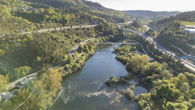 Aerial view of the Minho river flowing through a lush valley with bridges and highways Ourense, Province of Ourense, Spain.