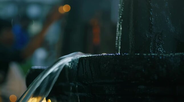 Water pouring over sacred Shiva Lingam in a Hindu temple ritual for worship and devotion.